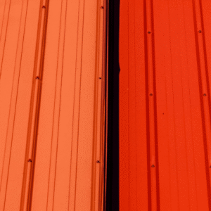 a close-up of a metal roof with visible loose fasteners and two sheets coming apart, highlighting the potential for panel misalignment and leaks if not properly secured.